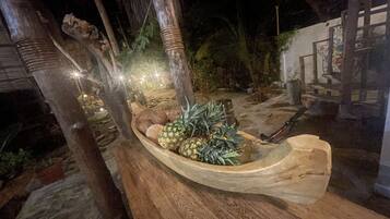 Un vaso a forma di barca di legno pieno di noci di cocco e ananas, posizionato su un pontile in legno.