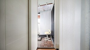 Un pasillo estrecho que lleva a una habitación con suelo de ladrillo y una silla blanca.