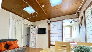 Una sala de estar moderna con un sofá, una mesa de comedor y un televisor montado en la pared.
