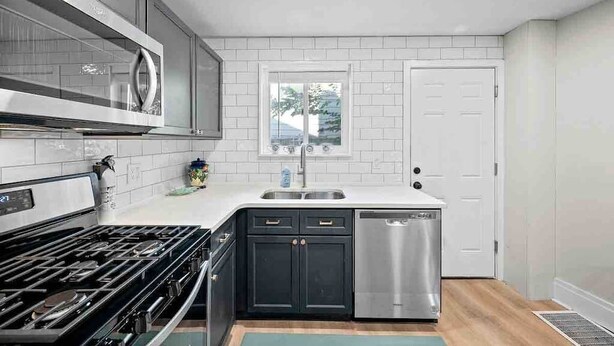 A modern kitchen with a gas stove, stainless steel dishwasher, and white subway tiles.