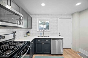 A modern kitchen with a gas stove, stainless steel dishwasher, and white subway tiles.