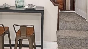 A staircase with wooden railings leading to a room with a brick wall and a carpeted floor.