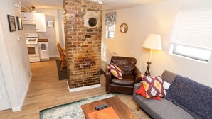 A living room with a brick fireplace, a sofa, a chair, and a coffee table. - Cozy & Comfy Cottage in the City - w/ parking! (Pittsburgh)