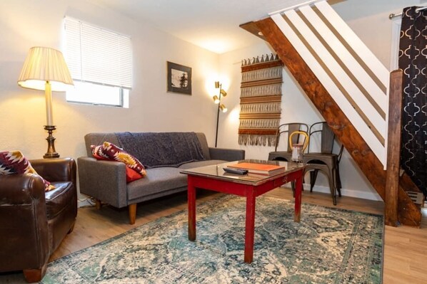 Un salon avec un canapé, une table basse, une lampe et un escalier.