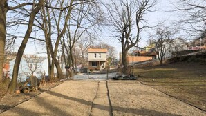 A pathway leading to a house with a red roof, surrounded by leafless trees and a grassy area. - Cozy & Comfy Cottage in the City - w/ parking! (Pittsburgh)