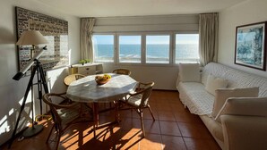 Una habitación con una mesa de comedor, sillas, un telescopio, un sofá y vista al océano.