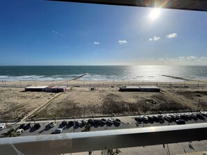 Blick auf einen Strand, im Vordergrund ein Parkplatz und ein klarer Himmel.