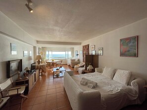 A hotel room with a bed, a desk, a chair, a TV, and a view of the sea. - Studio with an incredible ocean view (Setúbal)