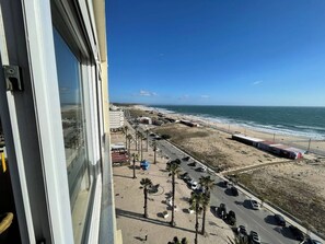 A coastal view from a high-rise building with a beach, parking area, and ocean in the background. - Studio with an incredible ocean view (Setúbal)