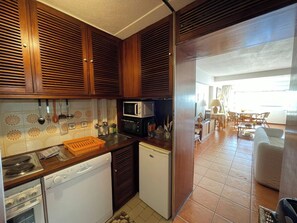 Eine kleine Küche mit Holzausstattung, einer Mikrowelle, einem Geschirrspüler und einem Kühlschrank.