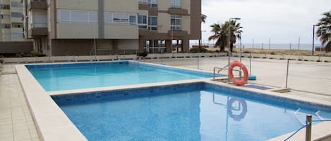 Piscina retangular com um boi de salvamento e uma palmeira ao fundo.