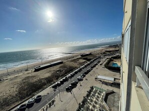 A coastal view from a high vantage point, overlooking a beach with parked cars and a clear sky. - Studio with an incredible ocean view (Setúbal)