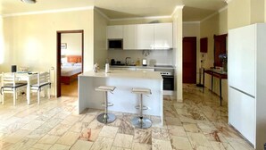 Una cocina moderna con una isla central, armarios blancos y un comedor con una mesa y sillas.