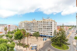 A multi-story hotel with a central courtyard, surrounded by other buildings. - Charming 2-bedroom apartment in Caparica (Almada)