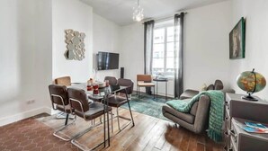 Una sala de estar moderna con comedor, televisor de pantalla plana, un globo terráqueo y un ventanal grande con cortinas.