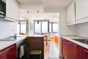 Una cocina moderna con una isla central, un comedor con vistas y una pared de acento roja.