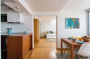 Una cocina moderna con armarios de madera, un comedor con mesa y sillas, y una sala de estar con sofá.