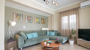 Una sala de estar con un sofá modular, una mesa de centro, un televisor y obras de arte en la pared.