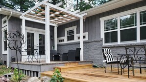 Un patio couvert avec des meubles d’extérieur, une pergola et un mur en pierre.