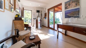 Une pièce avec un bureau en bois, une chaise en osier et une vue sur l’extérieur.