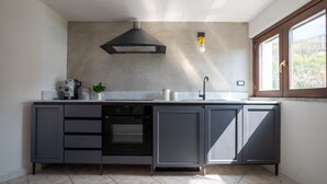 A modern kitchen with grey cabinetry, a built-in oven, and a window with a view of greenery.