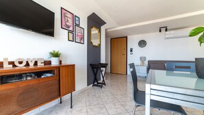 A modern living room with a TV, a coffee table, a dining table with chairs, and a sofa.