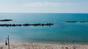A beach with calm waters, a sandy shore, and a rocky breakwater.