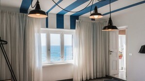A hotel room with a large window, curtains, and a bed.