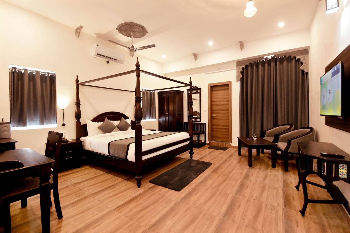 A four-poster bed with a wooden frame, a ceiling fan, and a flat-screen TV mounted on the wall.