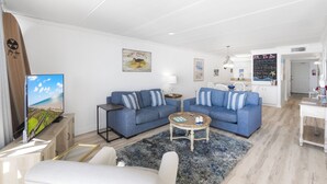 Un soggiorno moderno con due divani blu, un tavolino da caffè e una TV su un mobile in legno.
