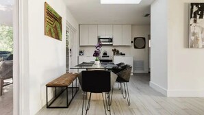 A modern kitchen with white cabinets, a dining area with a bench and chairs, and artwork on the walls. - Modern  Relaxing Zen ~ 5 ★  New pool, HotTub, Magic Garden!  (Wilton Manors)