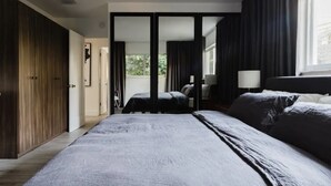 A modern bedroom with a large bed, a wardrobe, and a window with curtains. - Modern  Relaxing Zen ~ 5 ★  New pool, HotTub, Magic Garden!  (Wilton Manors)