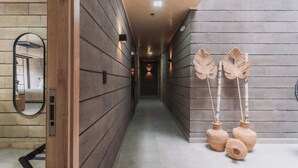 Um corredor com paredes de painel de madeira, um espelho e três vasos trançados no chão.