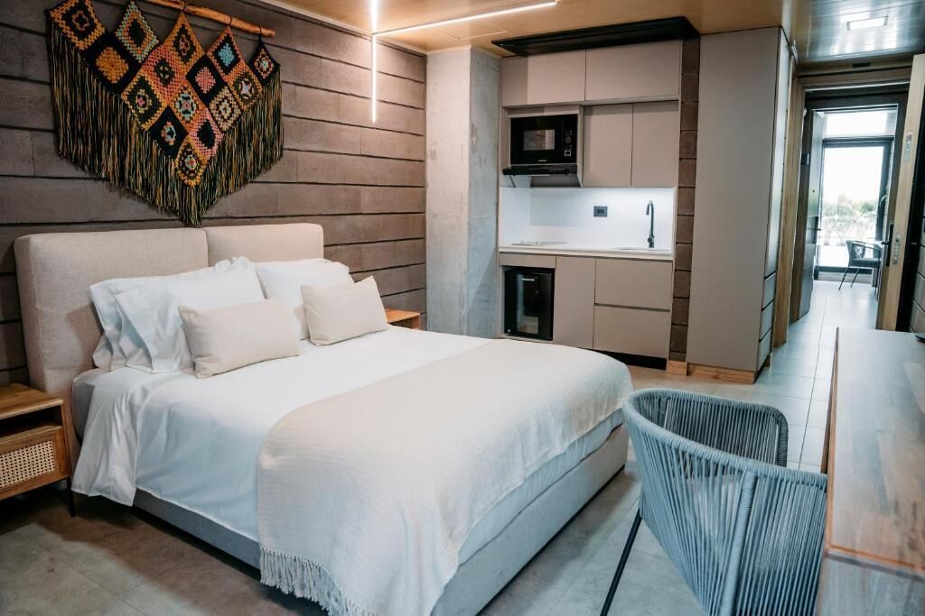 Une chambre moderne avec un grand lit, une petite kitchenette et une vue sur l’extérieur.