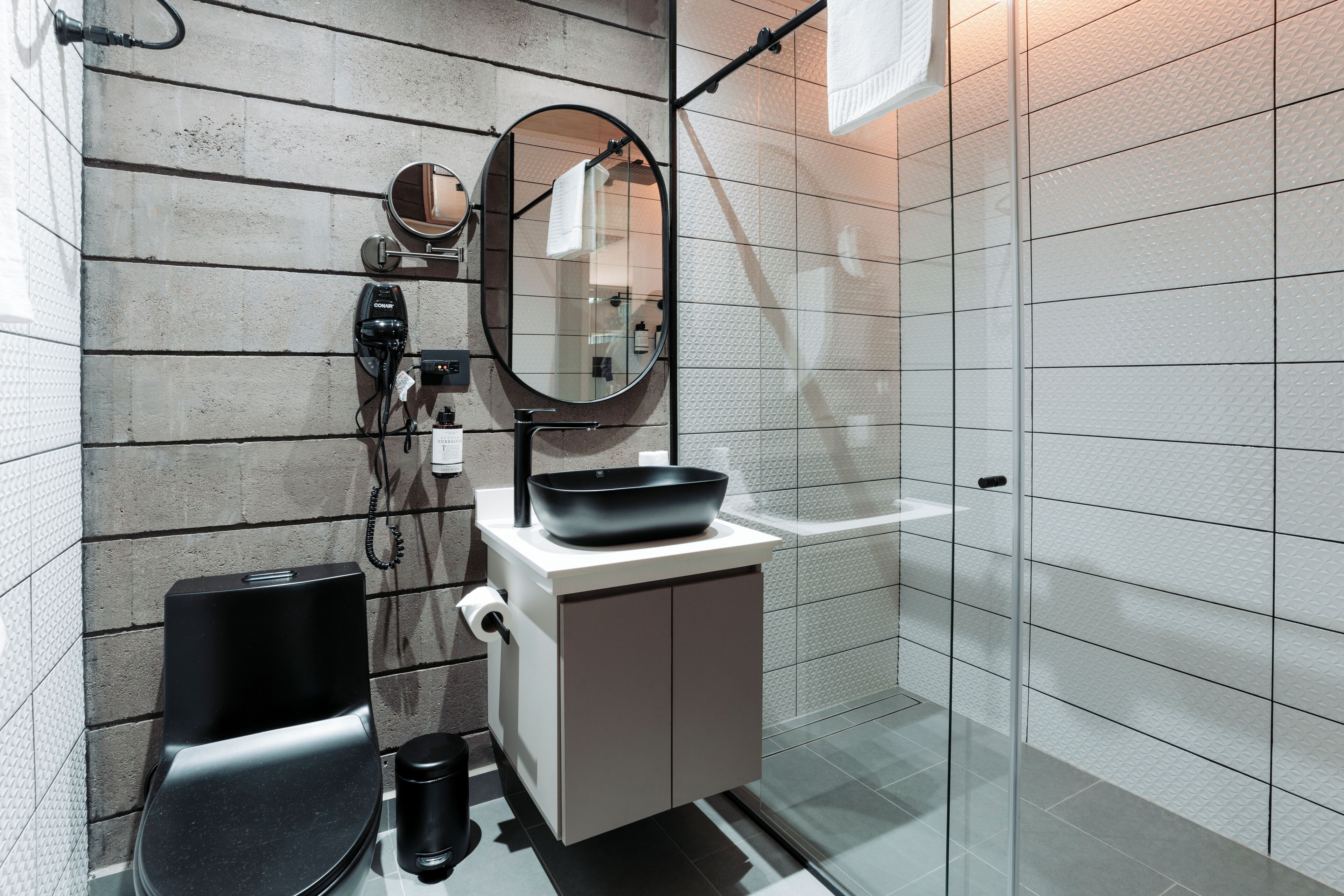 A modern bathroom with a toilet, bidet, sink, and mirror.