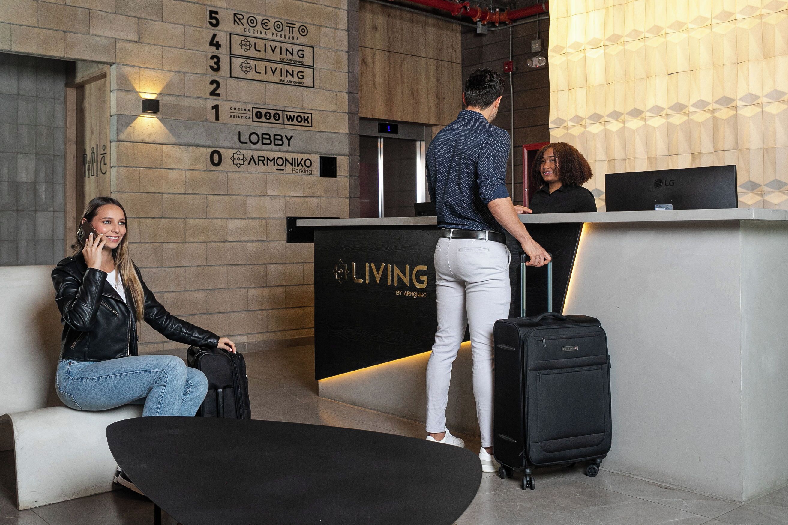 Un vestíbulo de hotel con una recepción, una zona de estar y una escalera.