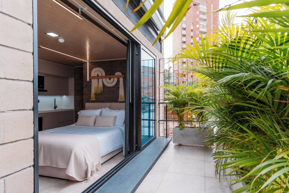 Een moderne slaapkamer met een bed, nachtkastje en uitzicht op de stad.