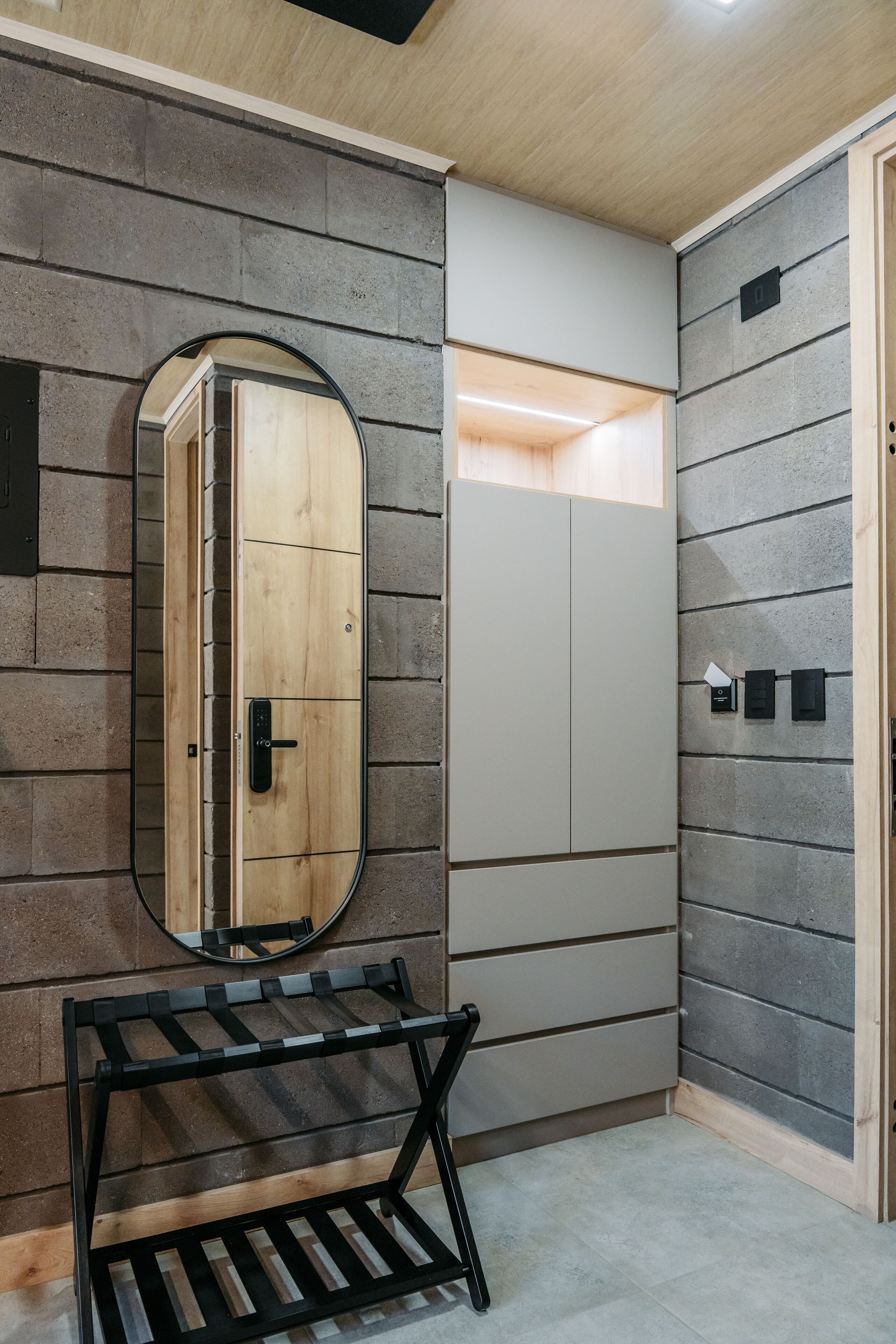 A modern bathroom with a wooden door, a mirror, and a black metal shelf.