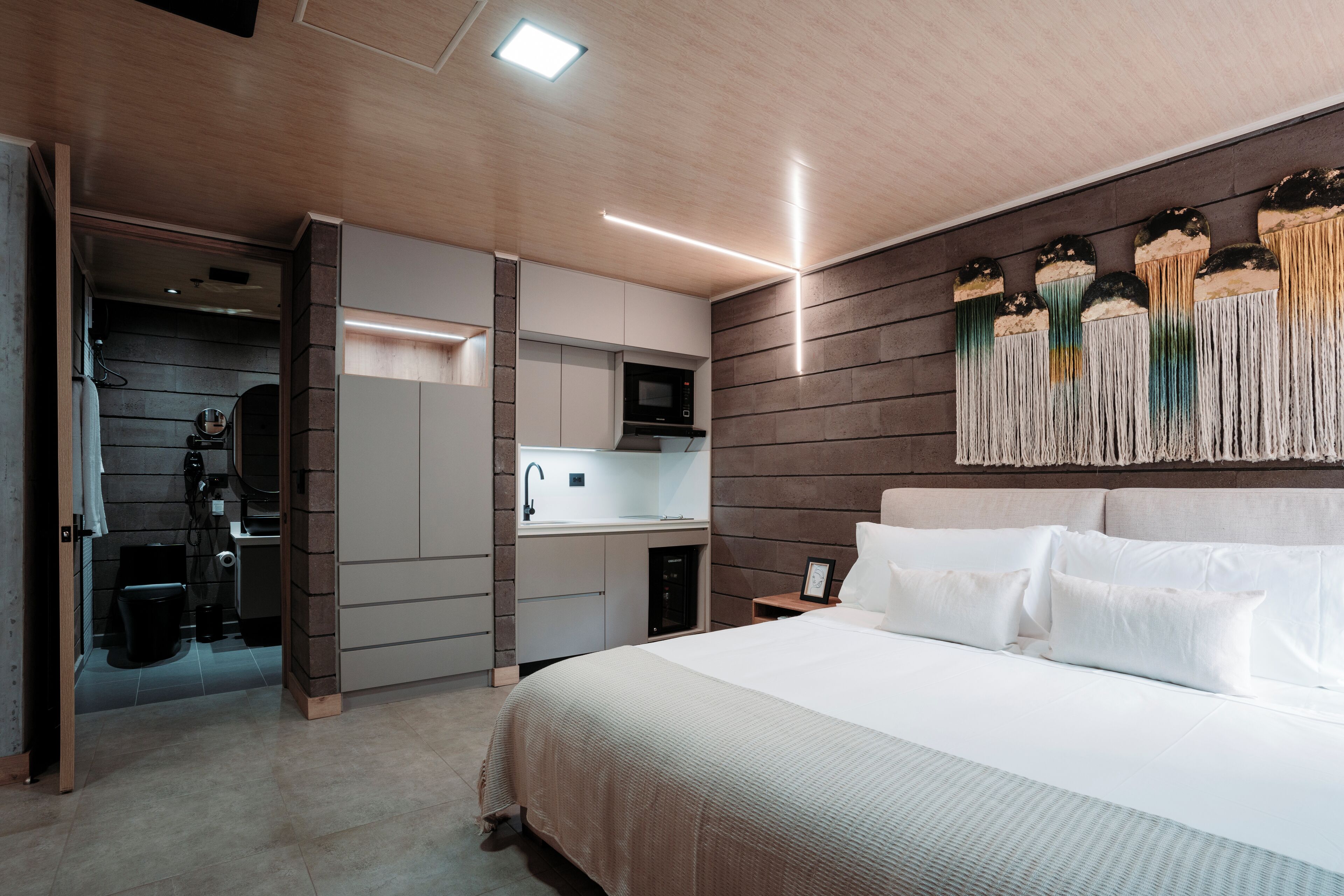 Een moderne slaapkamer met een groot bed, een inbouw bureau en een wandgemonteerde televisie.