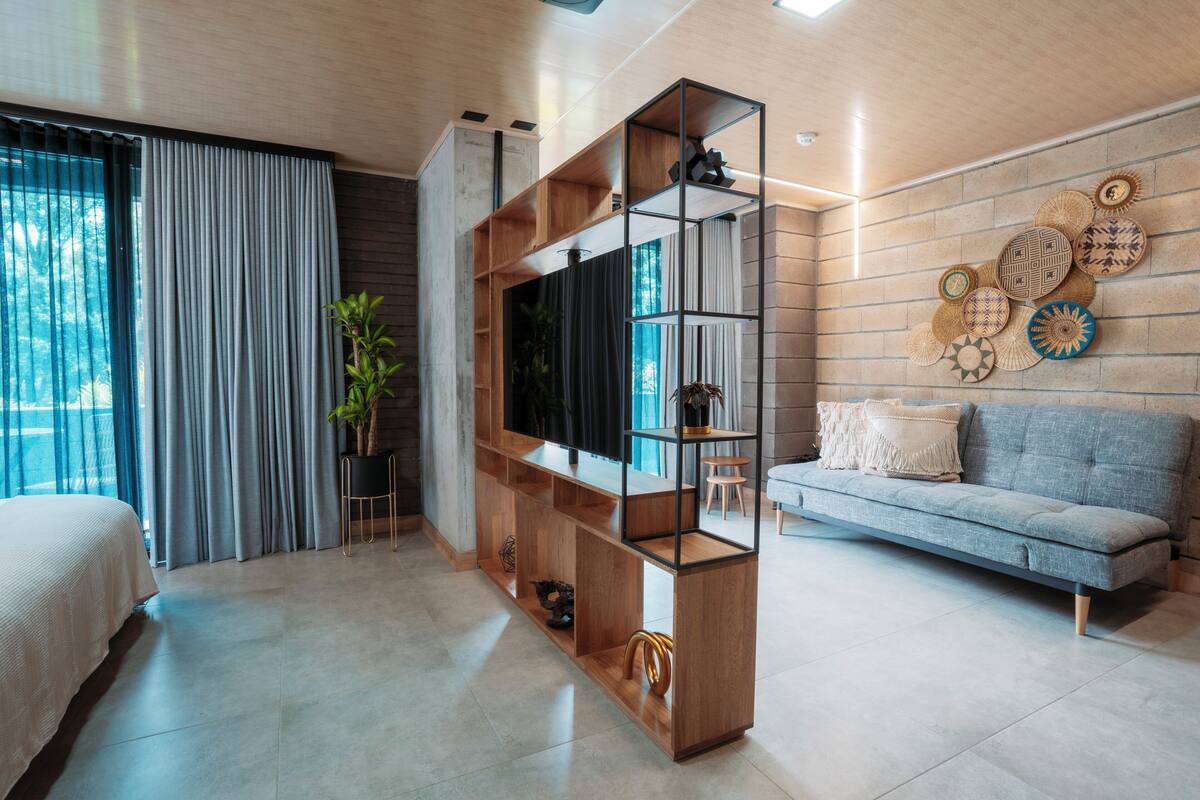 Een moderne woonkamer met een grijze bank, een houten tv-meubel en een wand versierd met geweven schotels.
