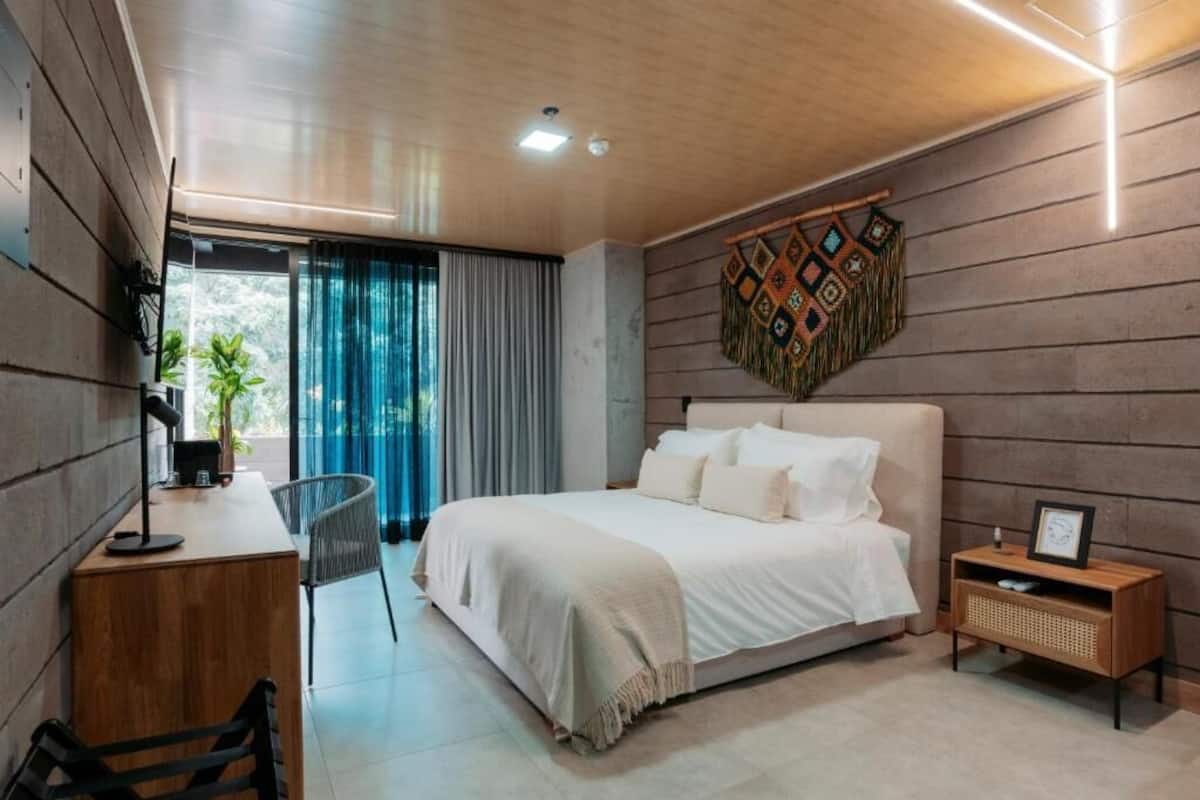 Een moderne slaapkamer met een groot bed, een bureau en een stoel.