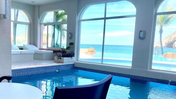 A swimming pool with a view of the ocean, a seating area with a white couch, and a small plant on the poolside. - Departamentos CB1 (Mazatlán)