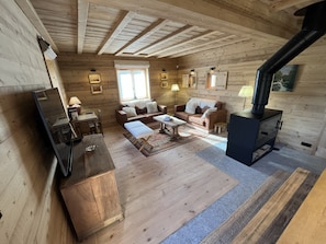 A log cabin interior with a sofa set, a dining table, a fireplace, and a television.