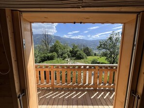 Una terraza de madera con vista a un paisaje verde y montañas.