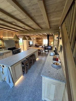 Una cocina amplia con encimeras de granito, armarios de madera y una isla grande con taburetes.