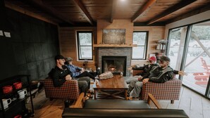 A cozy room with a fireplace, wooden furniture, and large windows. - North Shore Camping Co. (Beaver Bay)