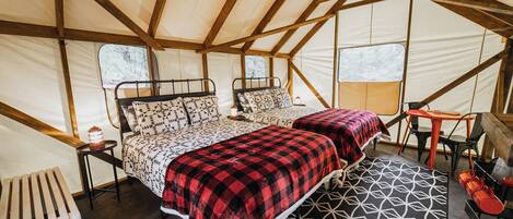 A tent with two beds, a table, chairs, and a radiator.