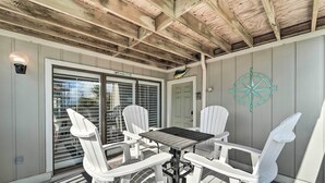 Eine überdachte Terrasse mit Tisch und Stühlen, einer Kompass-Wanddekoration und einer Tür mit Fenster.
