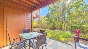 Eine Terrassengruppe mit Tisch und Stühlen, eine Holz-Pergola und Blick auf eine grüne Fläche mit Bäumen.