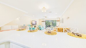 A bright, spacious room with a large white countertop, a ceiling fan, and a view of the outdoors through a sliding glass door. - Sea Me 9E–Close to Beach–Sleeps 6 (Panama City Beach)